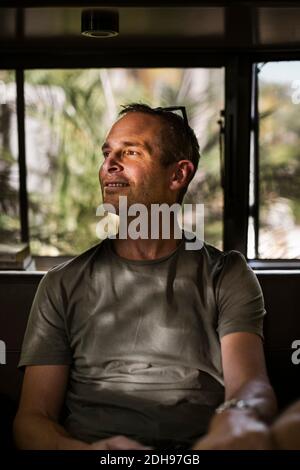 Smiling man looking away while sitting in camper trailer Stock Photo