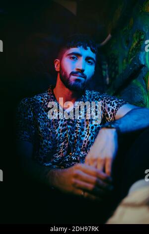 Portrait of confident bearded man sitting at illuminated bar Stock Photo
