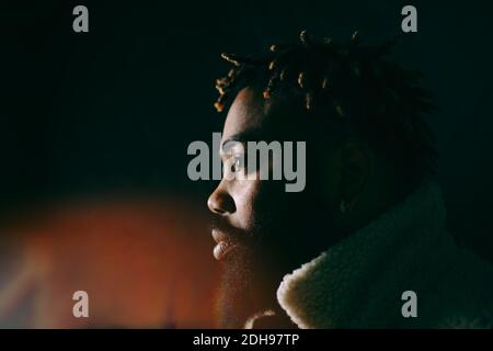 Side view of young bearded man with afro hairstyle looking away at restaurant Stock Photo