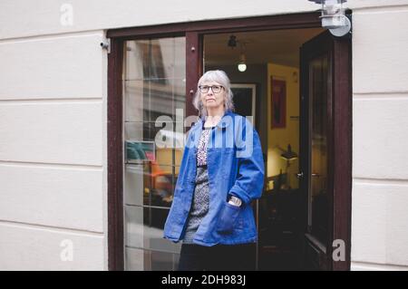 Senior female owner standing with hands in pockets outside jewelry store Stock Photo