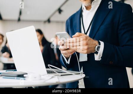 Midsection of male entrepreneur using phone while standing in office seminar Stock Photo