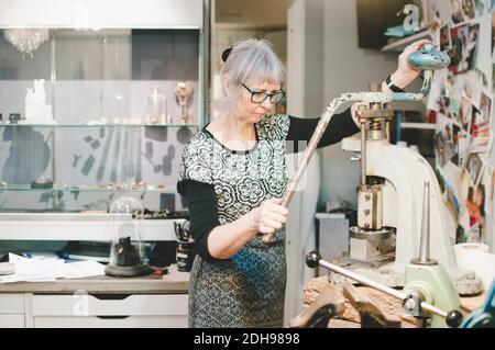 Senior woman working on vise grip in workshop Stock Photo