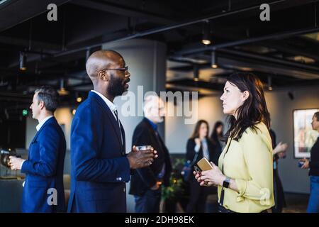 Side view of male and female coworker talking in office Stock Photo