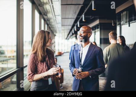 Female entrepreneur talking male coworkers in corridor at workplace Stock Photo
