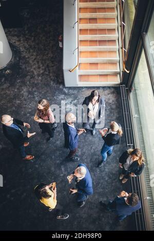 High angle view of business people discussing while standing at workplace Stock Photo