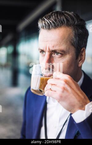 Businessman drinking tea while looking away at workplace Stock Photo
