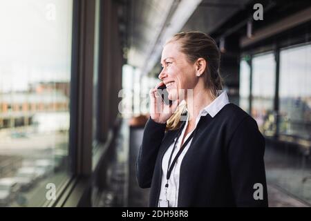 Smiling entrepreneur talking on mobile phone while standing at workplace Stock Photo