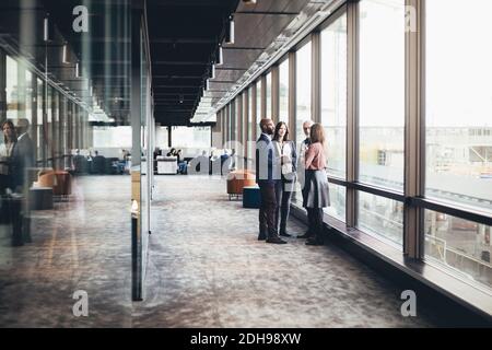Business colleagues discussing while standing in office corridor Stock Photo