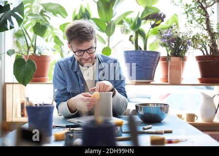 Young man shaping earthenware in pottery class Stock Photo