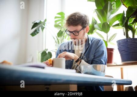 Young man making craft product in pottery class Stock Photo
