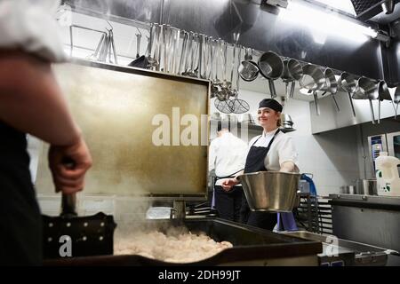 Smiling female chef working in commercial kitchen Stock Photo