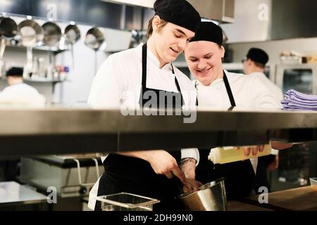 Young male chefs cooking together in commercial kitchen Stock Photo