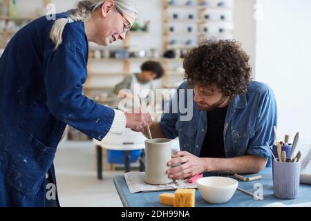 Male and female students learning pottery in class Stock Photo