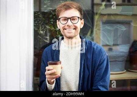 Portrait of smiling man having coffee outside art studio Stock Photo