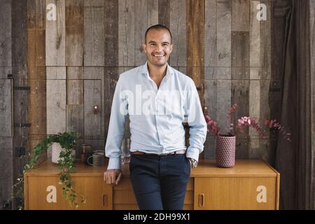 Portrait of happy businessman leaning on sideboard against wood paneling in portable office truck Stock Photo