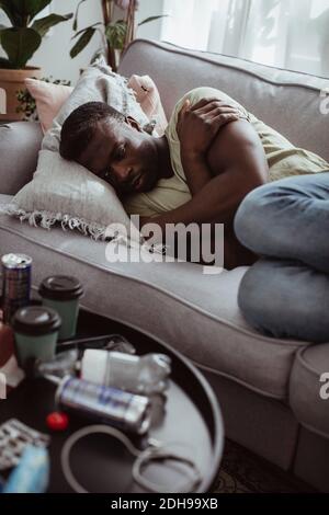 Worried man contemplating while lying on sofa Stock Photo
