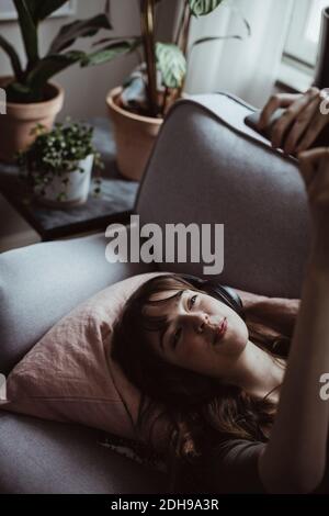 Smiling woman taking selfie while lying on sofa at home Stock Photo
