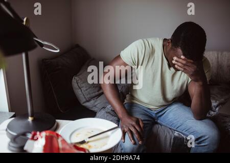 Worried man sitting on bed at home Stock Photo