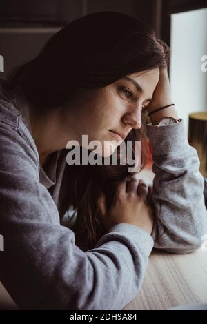 Sad woman looking away while sitting at table Stock Photo