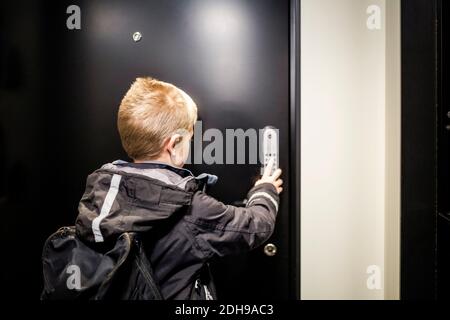 Boy unlocking combination security code on house door Stock Photo