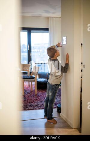 Full length of boy using digital tablet mounted on wall at modern home Stock Photo
