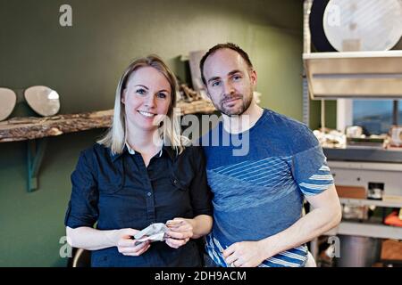 Portrait of confident couple standing in eyeglasses workshop Stock Photo