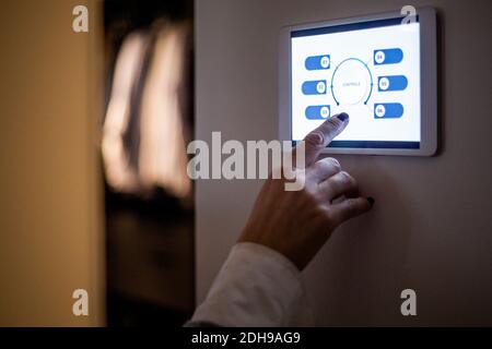 Cropped hand of woman using digital tablet mounted on wall at home Stock Photo