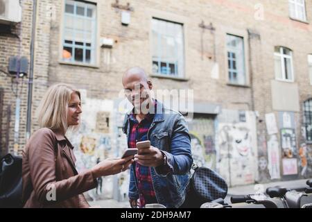 Multi-ethnic couple using mobile phones at bicycle sharing system Stock Photo