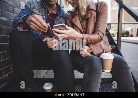 Midsection of couple using smart phones on steps Stock Photo