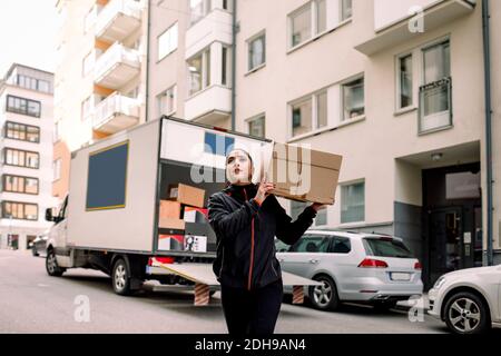 Young delivery woman carrying box on street Stock Photo