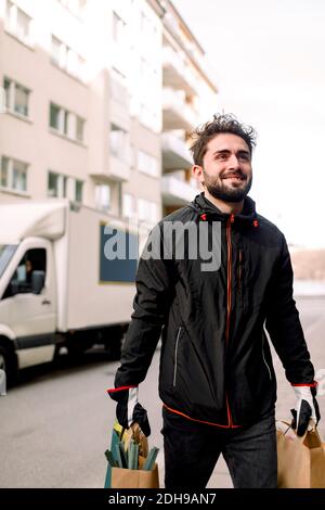 Confident young delivery man carrying grocery bags in city Stock Photo
