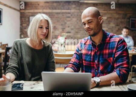 Couple using laptop at table in coffee shop Stock Photo