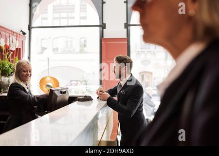 Happy businessman talking to female receptionist at hotel reception Stock Photo