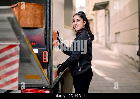 Side view portrait of young delivery woman with truck in city Stock Photo