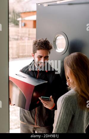 Female customer receiving package from delivery man Stock Photo