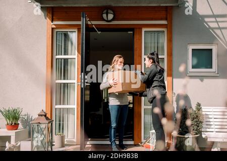 Female customer receiving box from young delivery woman Stock Photo