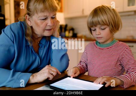 Senior woman looking at grandson using digital tablet Stock Photo