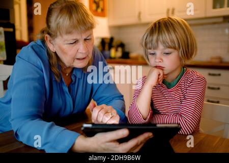 Boy looking at grandmother using digital tablet Stock Photo