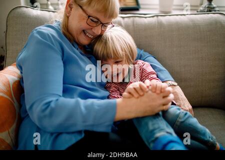 Happy boy sitting with grandmother on sofa at home Stock Photo
