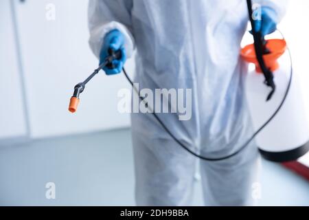 Mid section of health worker wearing protective clothes cleaning using disinfectant Stock Photo