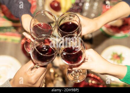 Friends with wine glasses in the restaurant for christmas. Cheers! Hands holding wine glass. Celebration, christmas and drink concept. Stock Photo