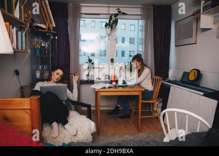 Young female roommates studying together in college dorm room Stock Photo