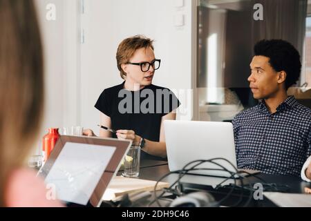 Businessman looking young genderblend professional during discussion in board room Stock Photo