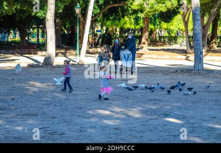 VALENCIA, SPAIN - Dec 09, 2020: Two beautiful little sisters having fun in the park with their parents. Stock Photo