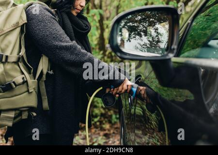 Midsection of mid adult woman charging electric car Stock Photo