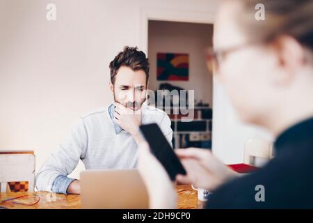 Man working on laptop while woman using mobile phone at home Stock Photo