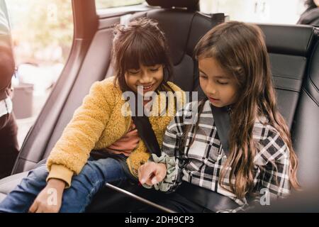 Sisters using digital tablet while sitting in electric car Stock Photo