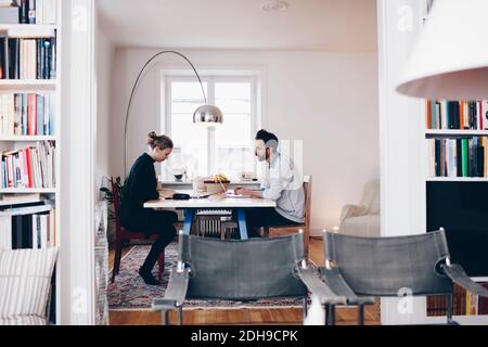 Side view of couple sitting at dining table working from home Stock Photo