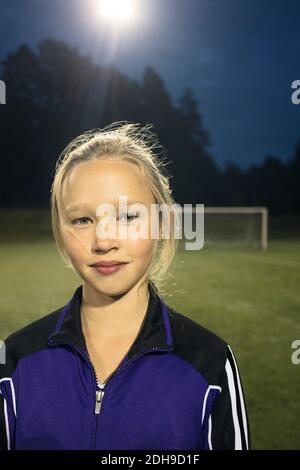 Portrait of confident girl standing on soccer field at night Stock Photo