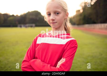 Portrait of confident girl standing with crossed arms at soccer field Stock Photo